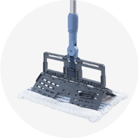 Un système de balai plat spécialisé, le Twixter de Vileda Professional. L'image montre un cadre de vadrouille double face en position semi-pliée, attaché à un manche bleu et argent. Une serpillière en microfibre blanche avec des rayures bleues est fixée sur le grand cadre gris rectangulaire, conçu pour un nettoyage performant et un essorage facile.